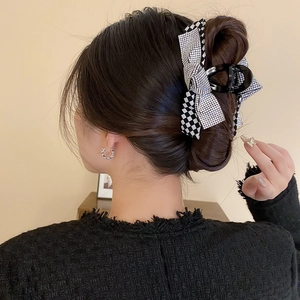 Detail of checkered bow hair claw clip with rhinestones worn on elegant bun hairstyle
