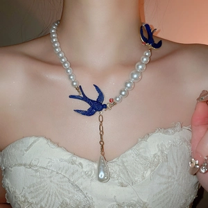 Detail of pearl necklace with blue swallow motifs and a large water drop pearl pendant