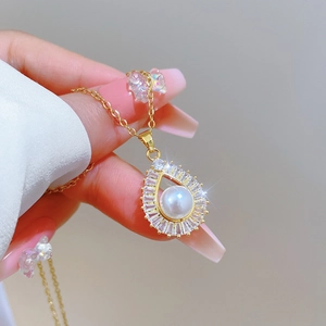 Detailed view of water drop pearl pendant with cubic zirconia on a gold titanium chain