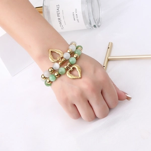 Detail of beaded heart bracelets featuring green cat eye stones and gold heart charms