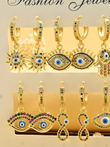 Detailed close-up of golden Hamsa Hand and Evil Eye earrings with colorful zircons