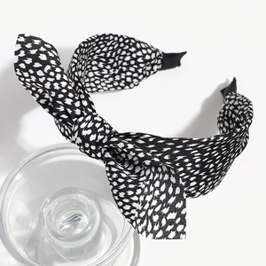 Detail view of fabric headband featuring a large black and white polka dot bow design