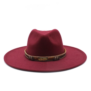 Detail of burgundy felt cowboy hat with woven beaded band and golden feather ornament