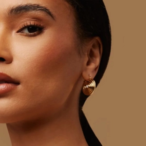 Minimalist gold titanium steel spiral hoop earrings displayed on a professional model