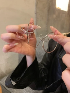 Close-up of silver bow hoop earrings showing the elegant metallic design and large size