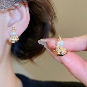 Close-up of gold gourd earrings with inlaid diamonds and pearls for a classic look