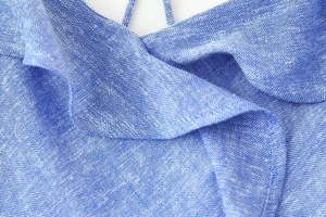 Close-up detail of blue linen blend tiered dress featuring ruffled neckline and thin straps