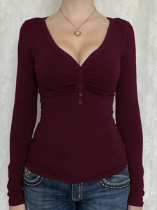 Detail shot of the burgundy long sleeve top featuring V-neck and button pleated texture