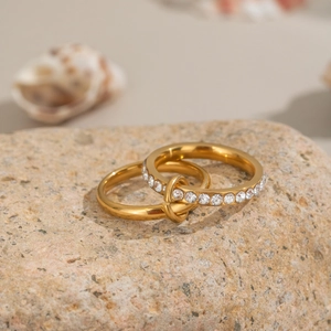 Macro detail of gold-plated double-layered ring with sparkling zirconia on textured stone