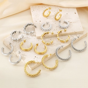 Detailed arrangement of gold and silver C-shaped earrings on a beige stone display