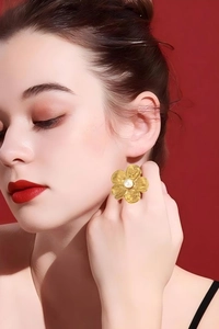 Close-up of golden vintage flower ring with pearl center and textured petals for women