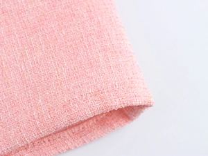 Close-up detail of high-quality pink tweed fabric with rich woven texture and fiber patterns