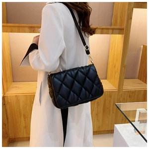 Close-up of quilted black leather texture and shoulder strap on a crossbody bag