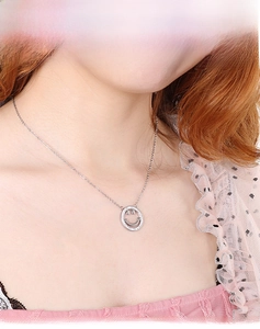 Close-up of a silver smiley face necklace with sparkling crystals on a model's neckline