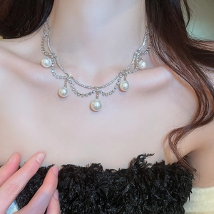 Detail shot of a double-layer silver necklace with rhinestones and five pearl pendants