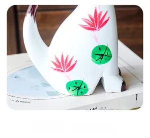 Detail of hand-painted white cat figurine featuring pink lotus and green leaf patterns
