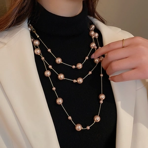 Close-up of elegant multi-layer pearl necklace with golden chains on a model