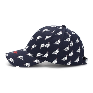 Detailed side view of navy baseball cap featuring white pigeon print and red accent