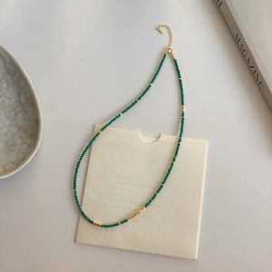 Detail of emerald green bead necklace with gold cylinder accent and lobster clasp closure