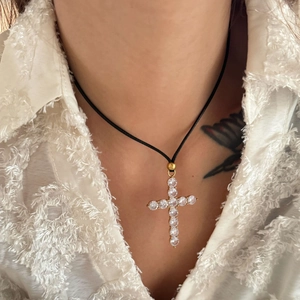 Cross pendant necklace with zircon stones on a black cord worn by a model