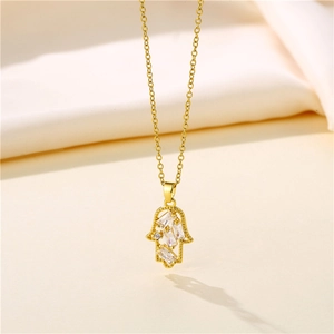 Goldene Hamsa-Halskette mit Zirkonia-Anhänger auf weichem weißem Seidenhintergrund