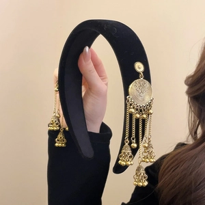 Detail of black velvet headband featuring ethnic style gold bells and tassel earrings