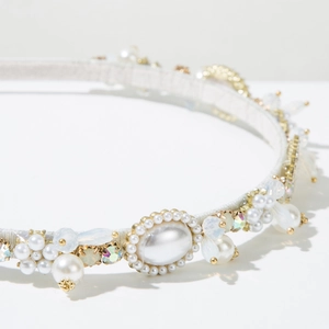Dettaglio di elegante cerchietto con perle, cristalli e base in metallo dorato