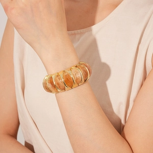 Close-up of a vintage elastic bracelet featuring amber marble resin and gold metal segments