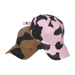 Close-up of pink and coffee cow print baseball caps in twill cotton fabric