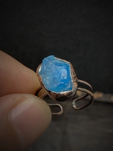 Macro detail of handmade bronze ring featuring a natural irregular blue raw gemstone