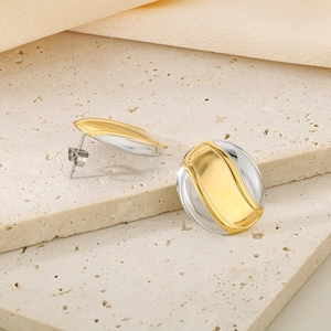 Macro detail of oval two-tone 18K gold and silver stainless steel stud earrings