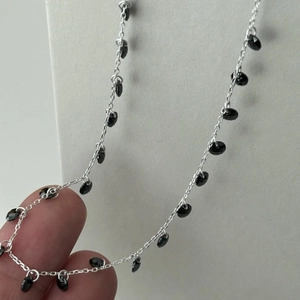 Macro detail of 925 sterling silver chain with small faceted black gemstone beads