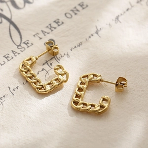 Detailed close-up of gold-plated Cuban chain link hoop earrings on a vintage paper background