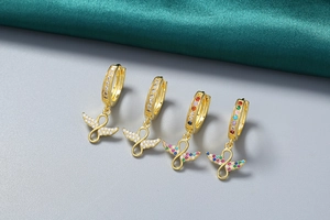 Détail de boucles d'oreilles en or 18 carats avec ailes infinies et zircons colorés