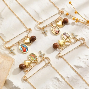 Detail of gold safety pin pendant necklaces with religious icons and wooden beads
