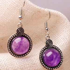 Détail de boucles d'oreilles vintage en argent avec résine marbrée mauve et spirale en métal