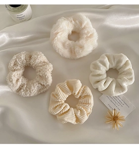 Set of four plush cream scrunchies in velvet and corduroy textures on silk background