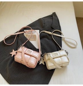Détail de sacs bandoulière tissés en rose et crème avec chaîne en métal et décor étoile