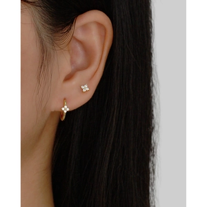 Golden S925 silver clover earrings set with white zircon stones on model's ear