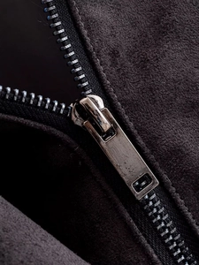 Gros plan du zip en métal argenté sur la texture en daim noir de la veste