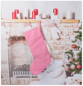 Détail d'une chaussette de Noël rose en feutre avec paillettes dorées sur cheminée