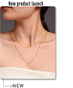 Nahaufnahme einer zweilagigen goldenen Herzenskette mit funkelnden Kristallen an einem Model
