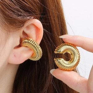 Macro view of gold spiral textured ear cuff with clip-on design on ear cartilage