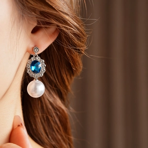 Dettaglio dell'orecchino vintage con gemma blu, strass e perla bianca a goccia