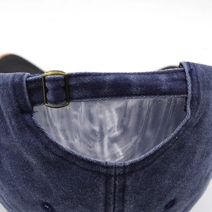 Detail view of washed navy denim baseball cap featuring vintage bronze metal buckle