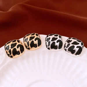 Detail of square vintage earrings with black enamel animal patterns on gold and silver metal