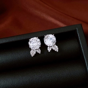 Macro shot of silver flower earrings with zircon stones on dark silk fabric