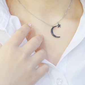 Macro shot of silver crescent moon necklace with black pave-set star and moon pendants
