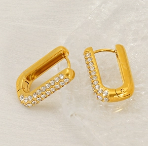 Detailaufnahme goldener U-förmiger Ohrringe mit Mikropavé-Kristallen auf Stoff