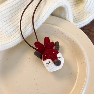 Close-up of a cute plush reindeer hair tie in red and white on a ceramic tray